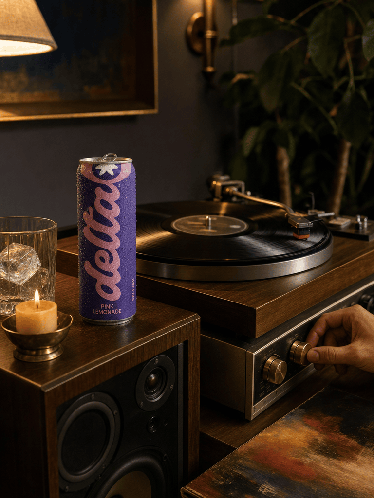 Vinyl record spinning on a wood-and-brass turntable, a Bold Pink Lemonade can on the speaker, dim warm lamp